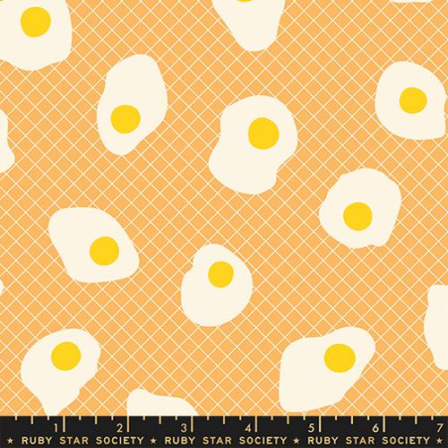 Pattern of fried eggs with yellow yolks on a peach background, featuring a ruler at the bottom.