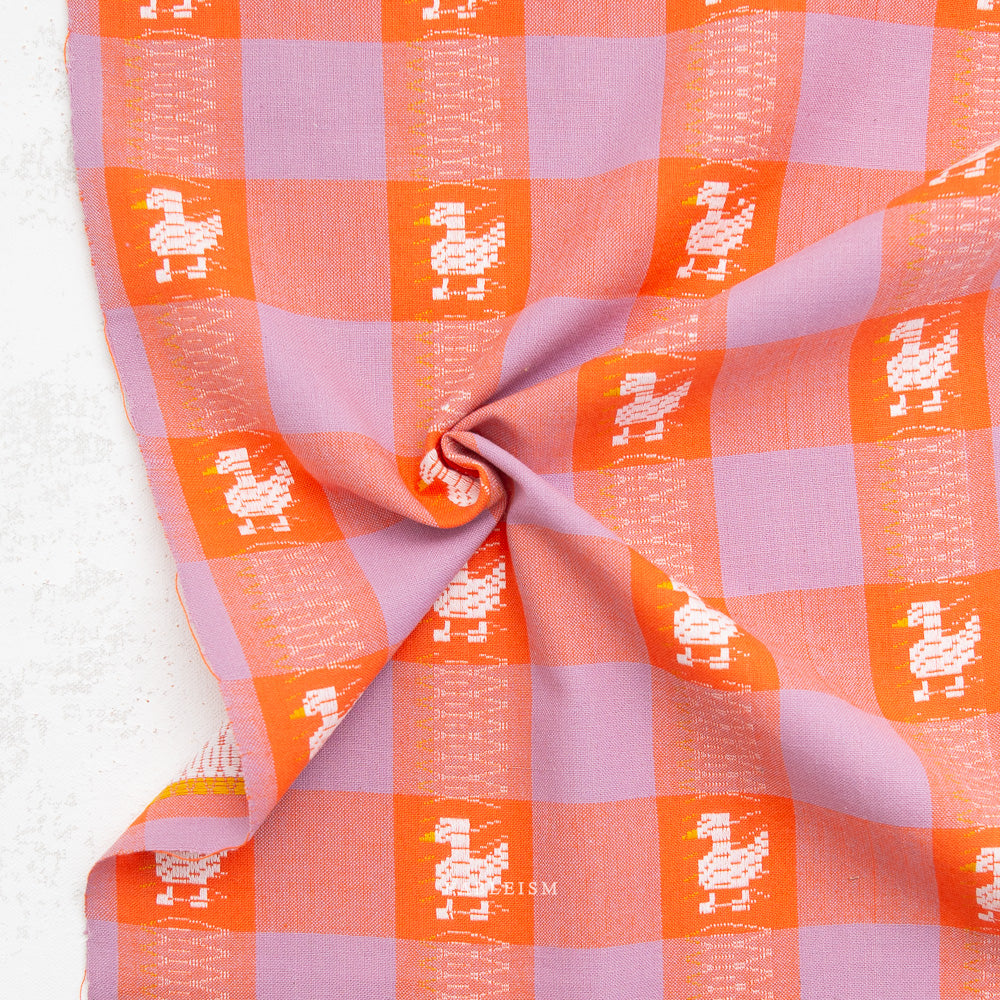 Checkered fabric with orange and pink squares and white patterns on a white background