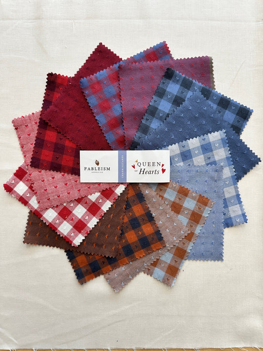 Queen of Hearts Charm Squares featuring a colorful splay of red, mraoon, blue and white and brown fabrics with checkers and tiny hearts