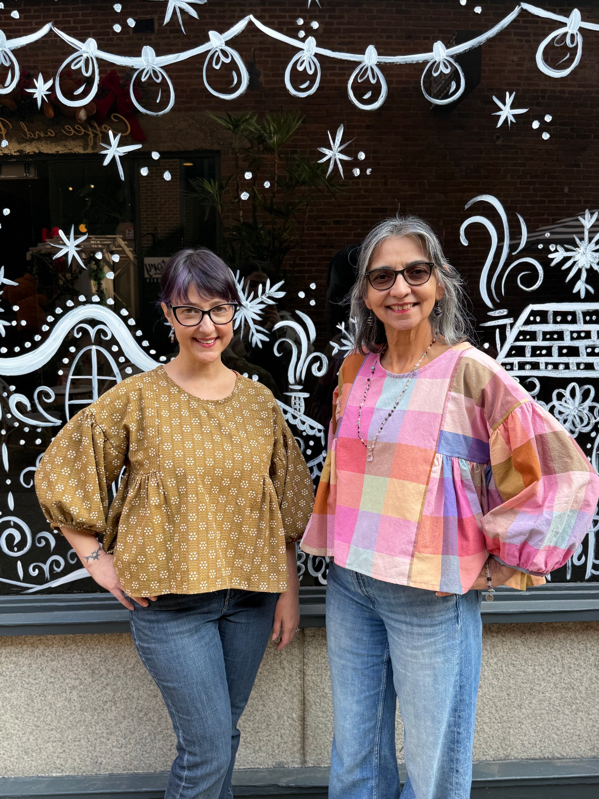 Darcy & Lana each wear a cropped puffy sleeve blouse, one in mustard the other in pastel plaid