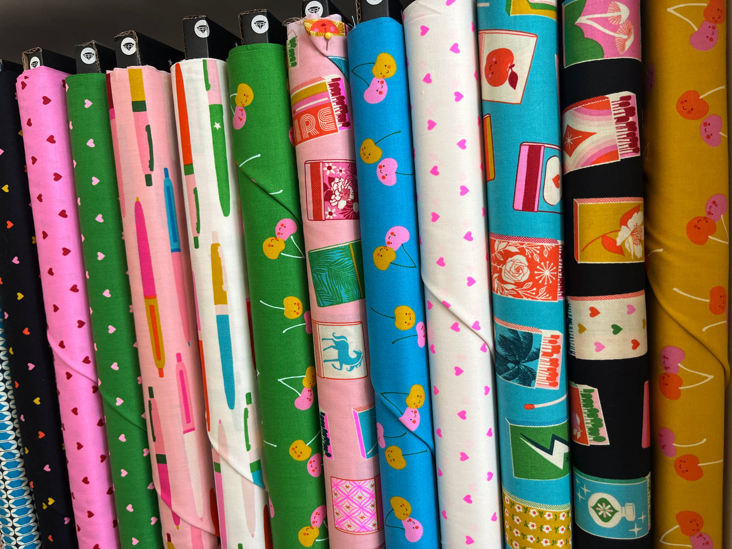 Row of colorful fabric rolls with various patterns on a black background