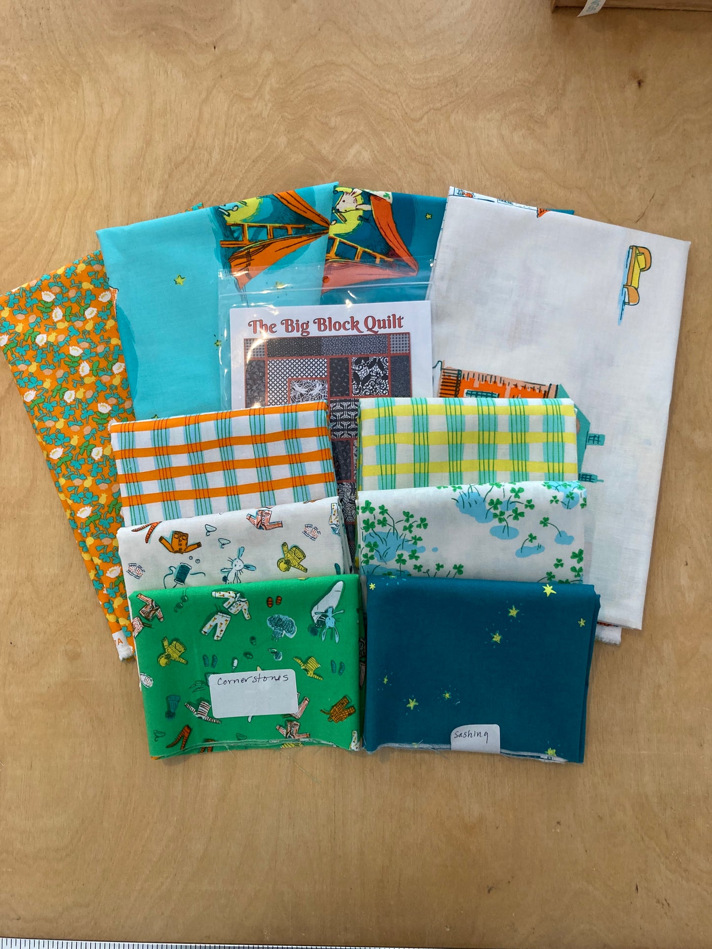 precut fabric in greens, blues and oranges with a quilt pattern