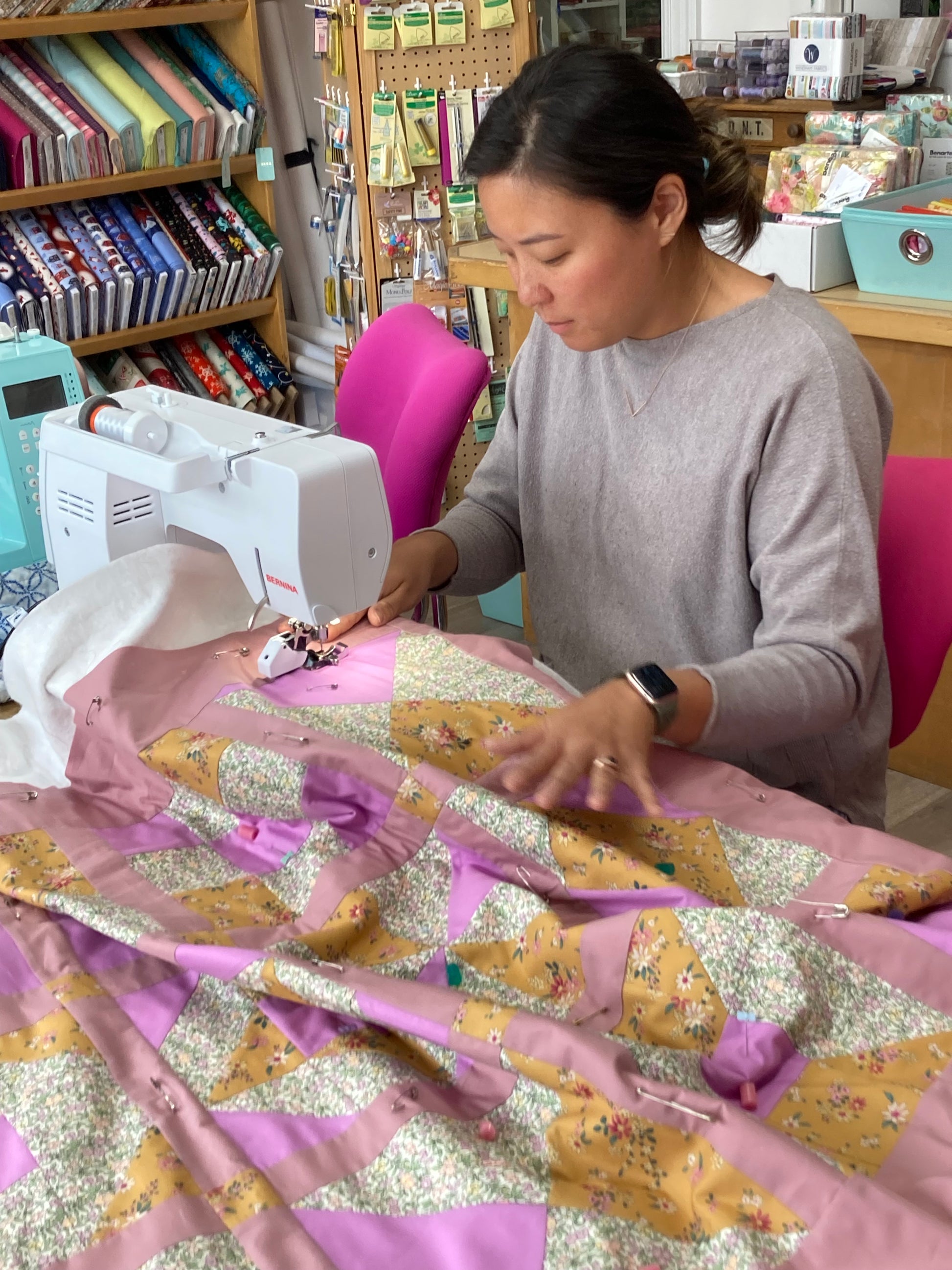 a woman working on a sewing machine with a quilt
