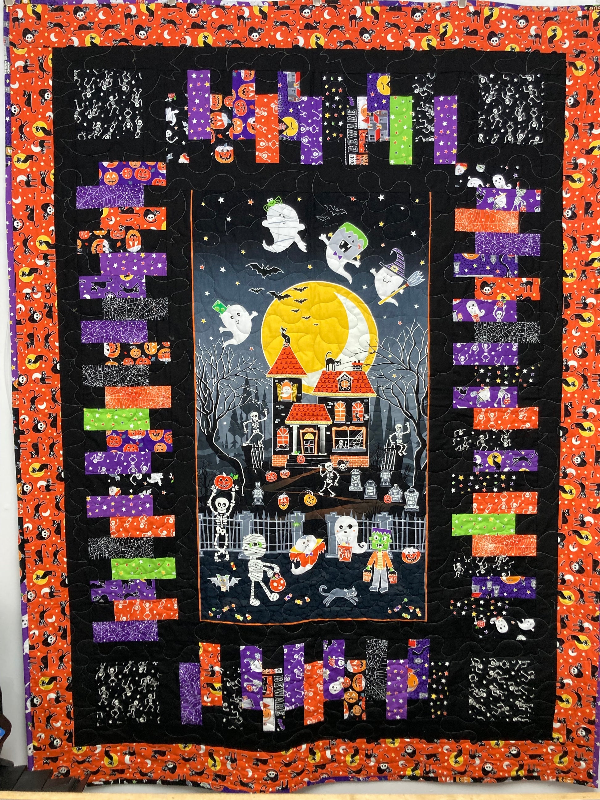 cute haunted house quilt with skeletons black, orange and purple