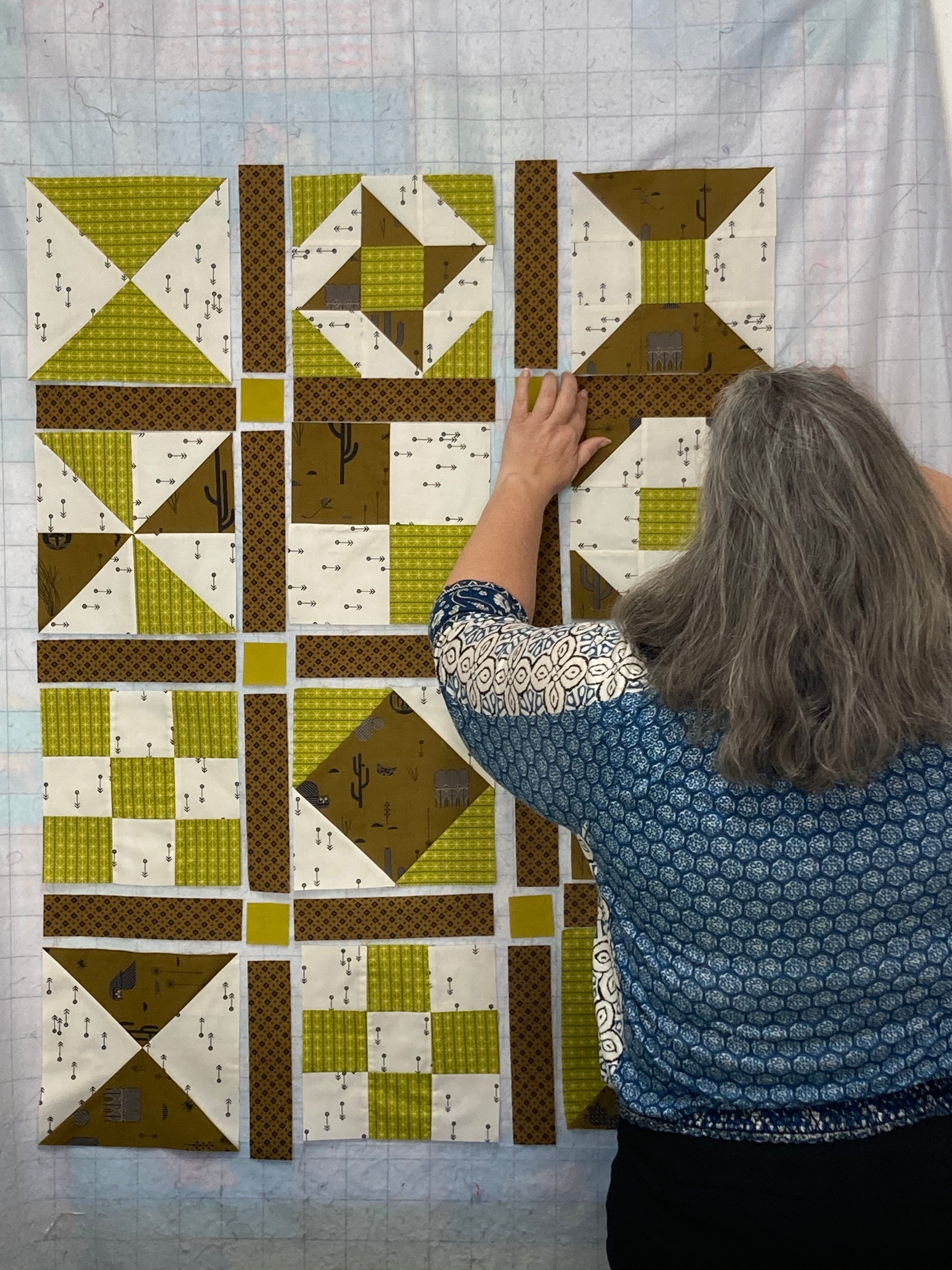 a person placing fabric quilt blocks on a wall