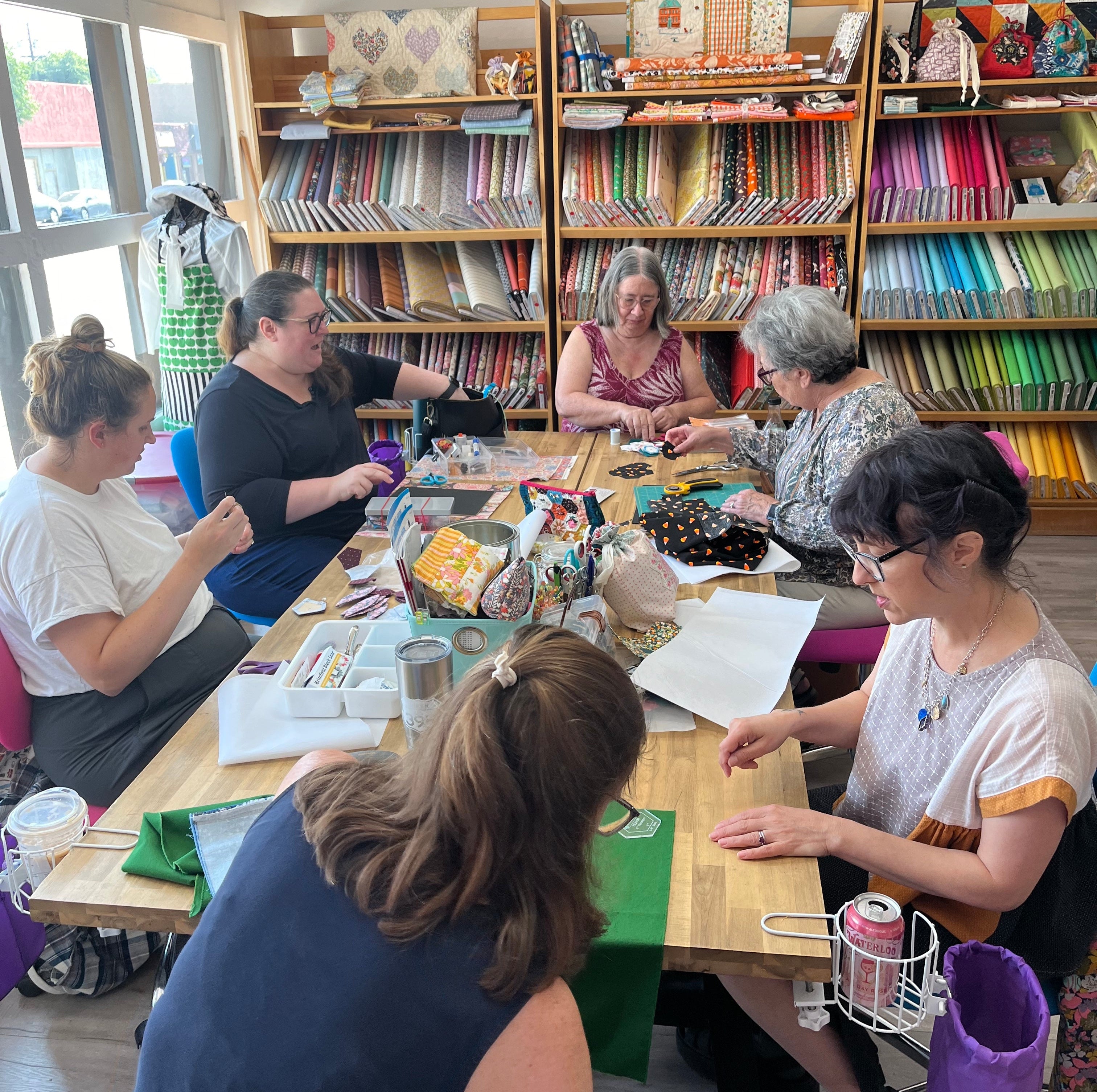 women working on sewing projects sitting around a table