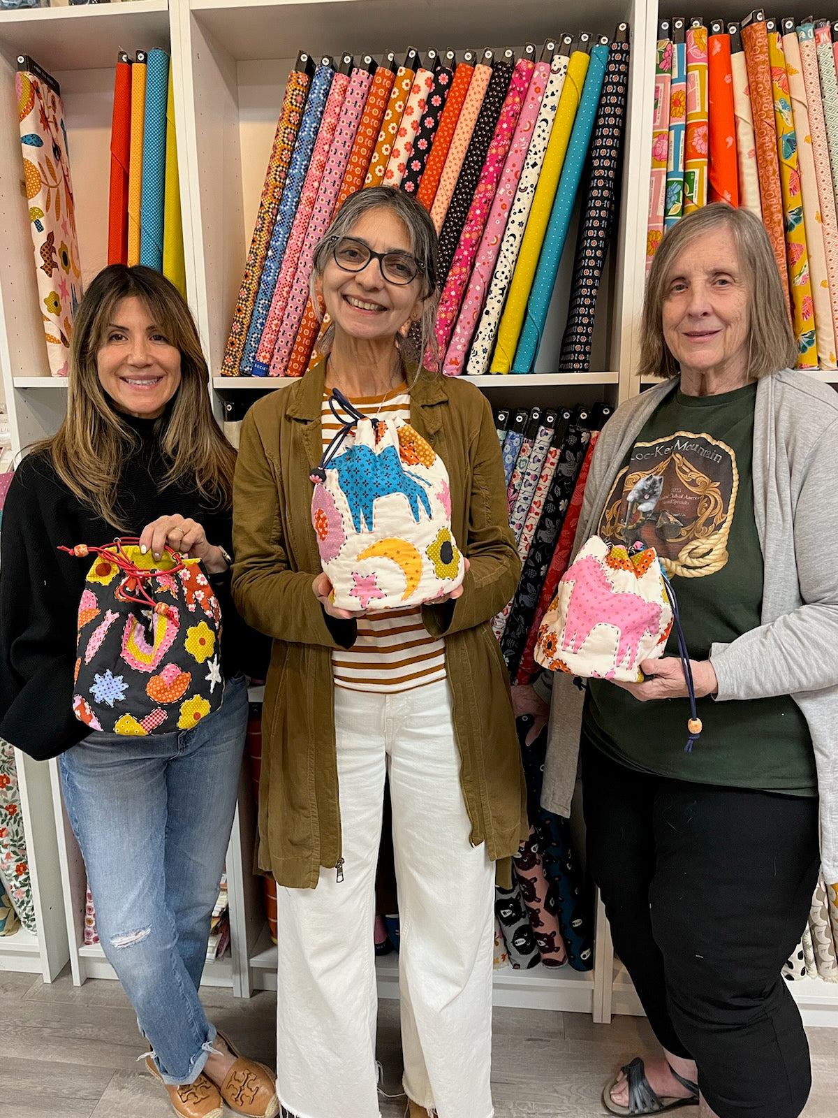 three women posing with three different sashiko rice bags 