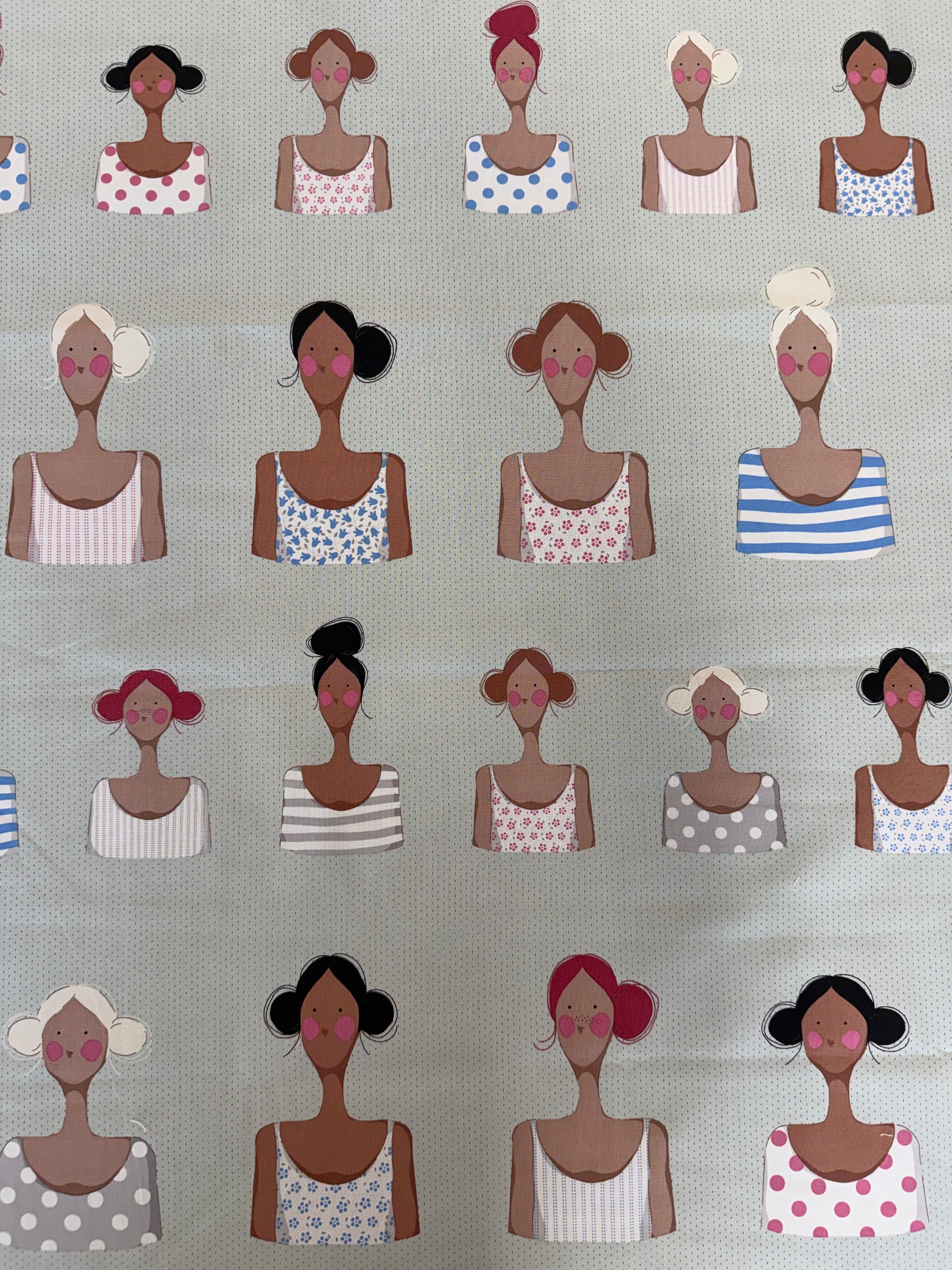 A close-up of a fabric or wallpaper pattern featuring stylized illustrated women in various hairstyles, skin tones, and colorful patterned camisoles on a light gray textured background.
