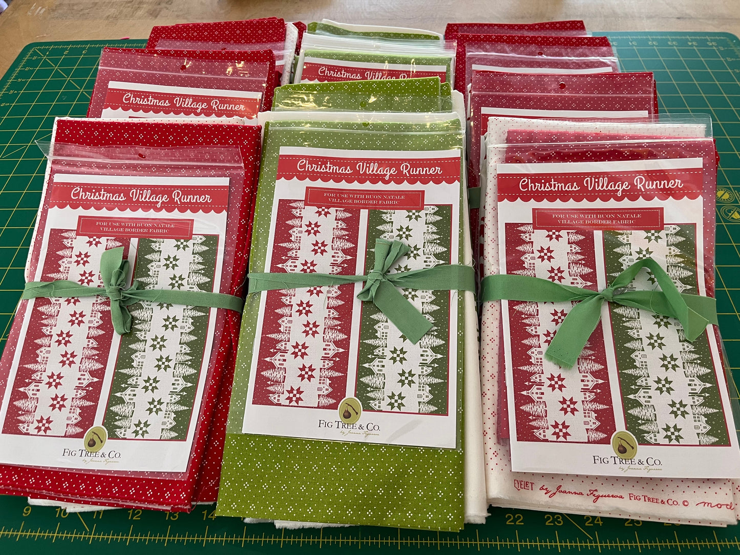 Set of Christmas-themed table runners with red and green designs on a green cutting mat.