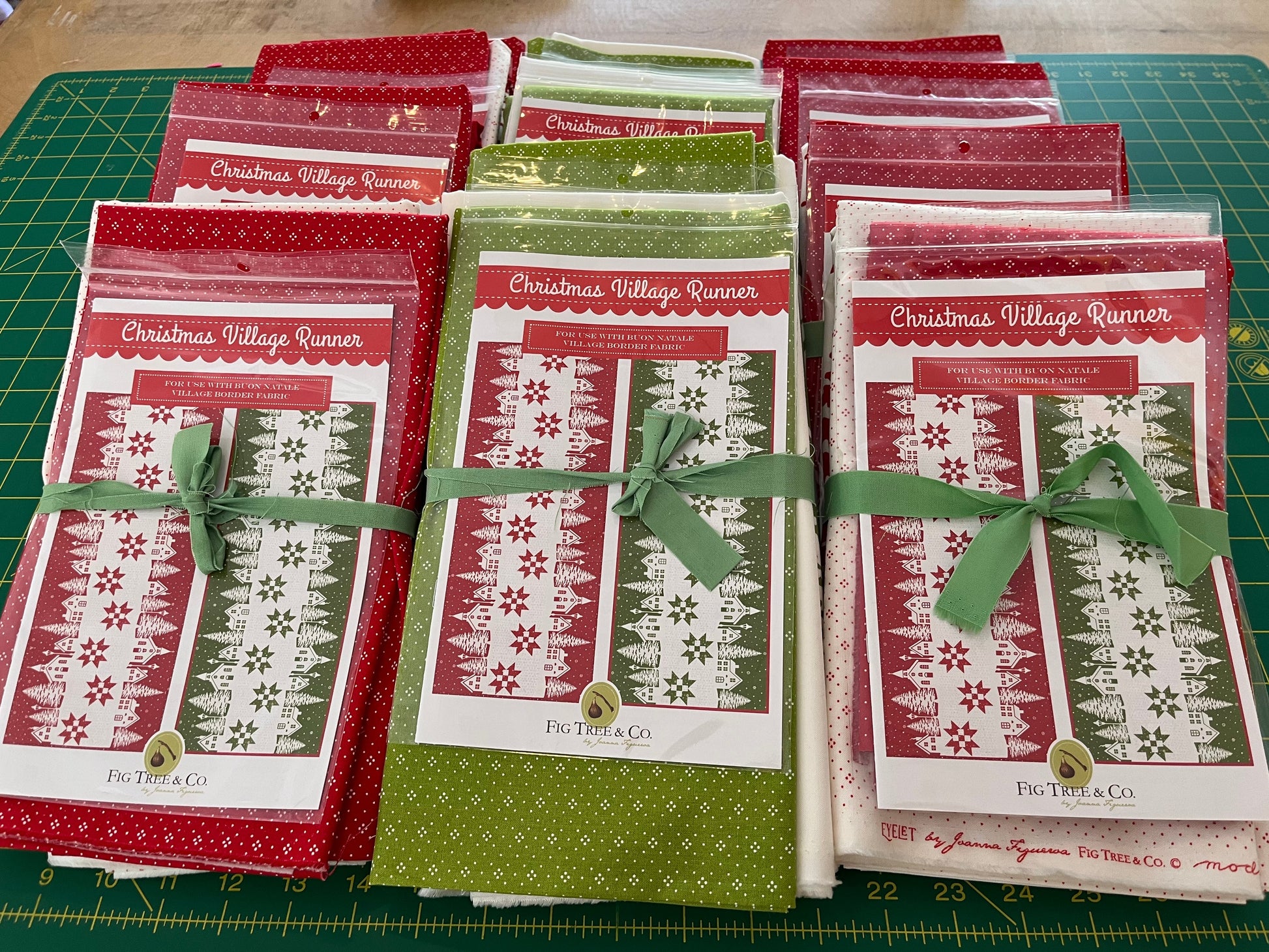 Set of Christmas-themed table runners with red and green designs on a green cutting mat.