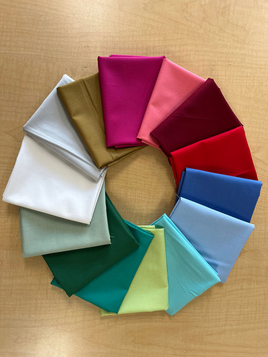 Circular arrangement of folded fabric swatches in various colors on a wooden surface