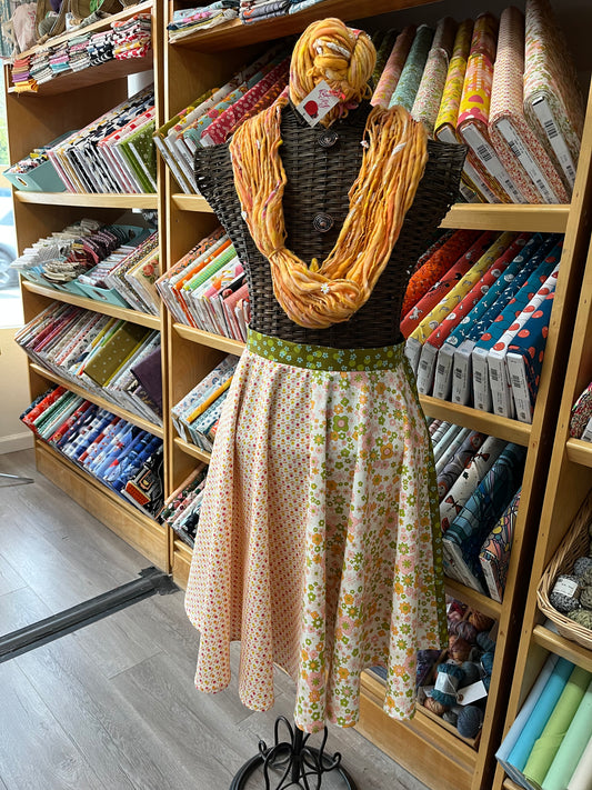 Mannequin wearing a patterned skirt and yellow scarf in a fabric store