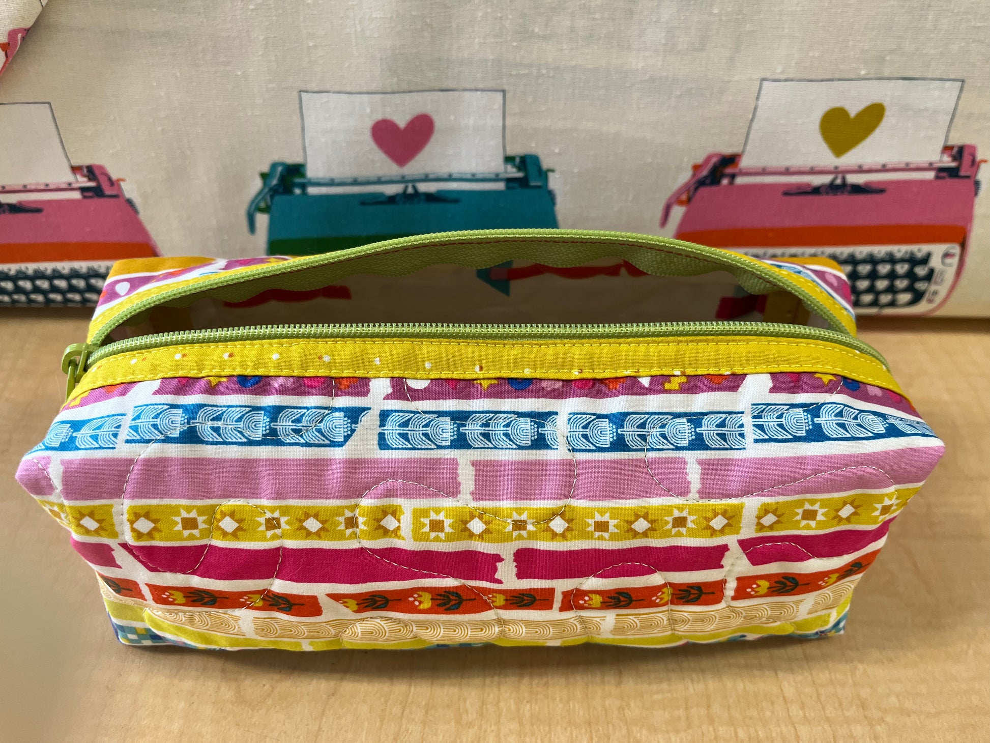 Colorful striped pencil case with a yellow zipper on a wooden surface.