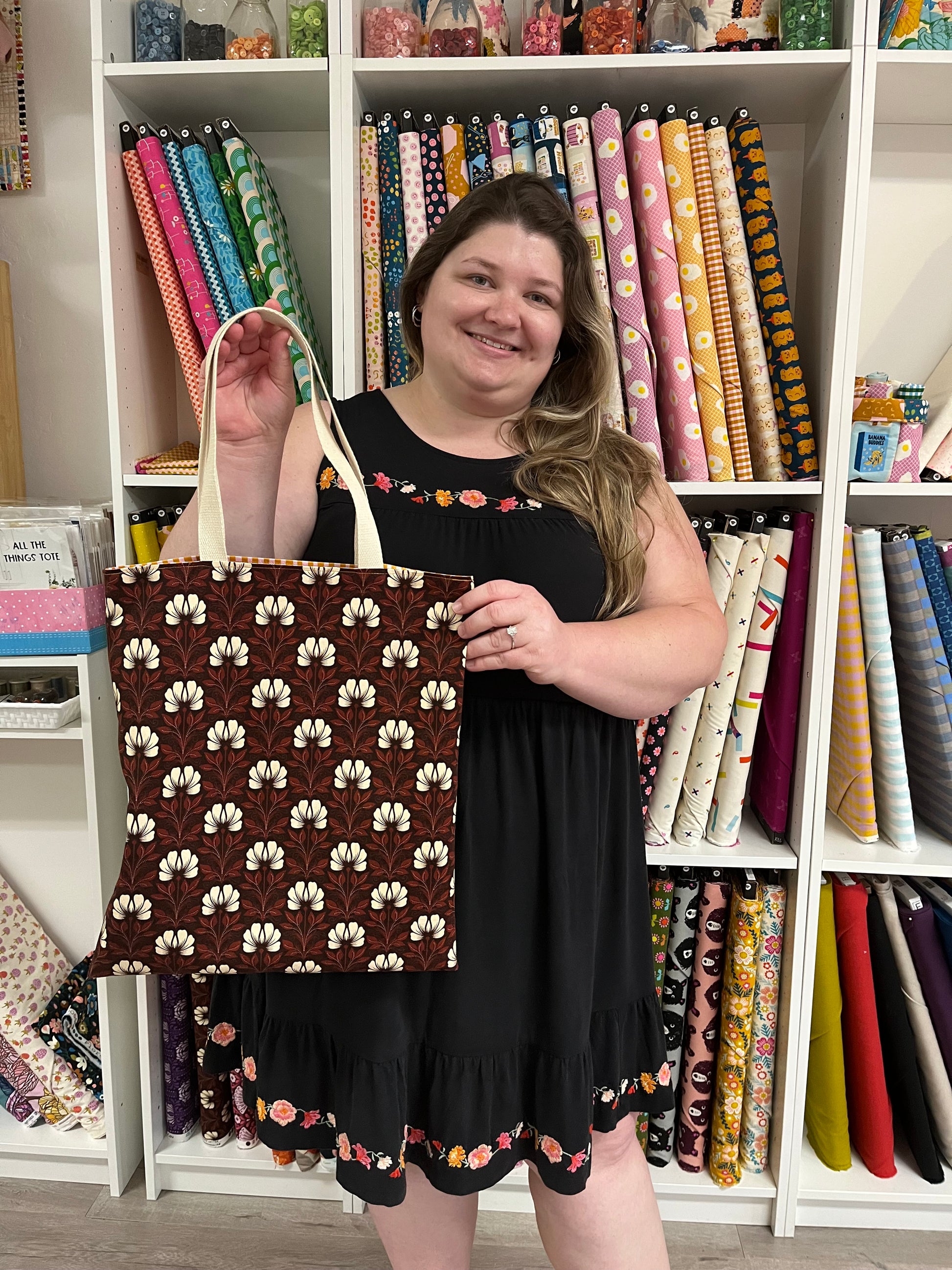A person holding a brown and beige floral tote bag