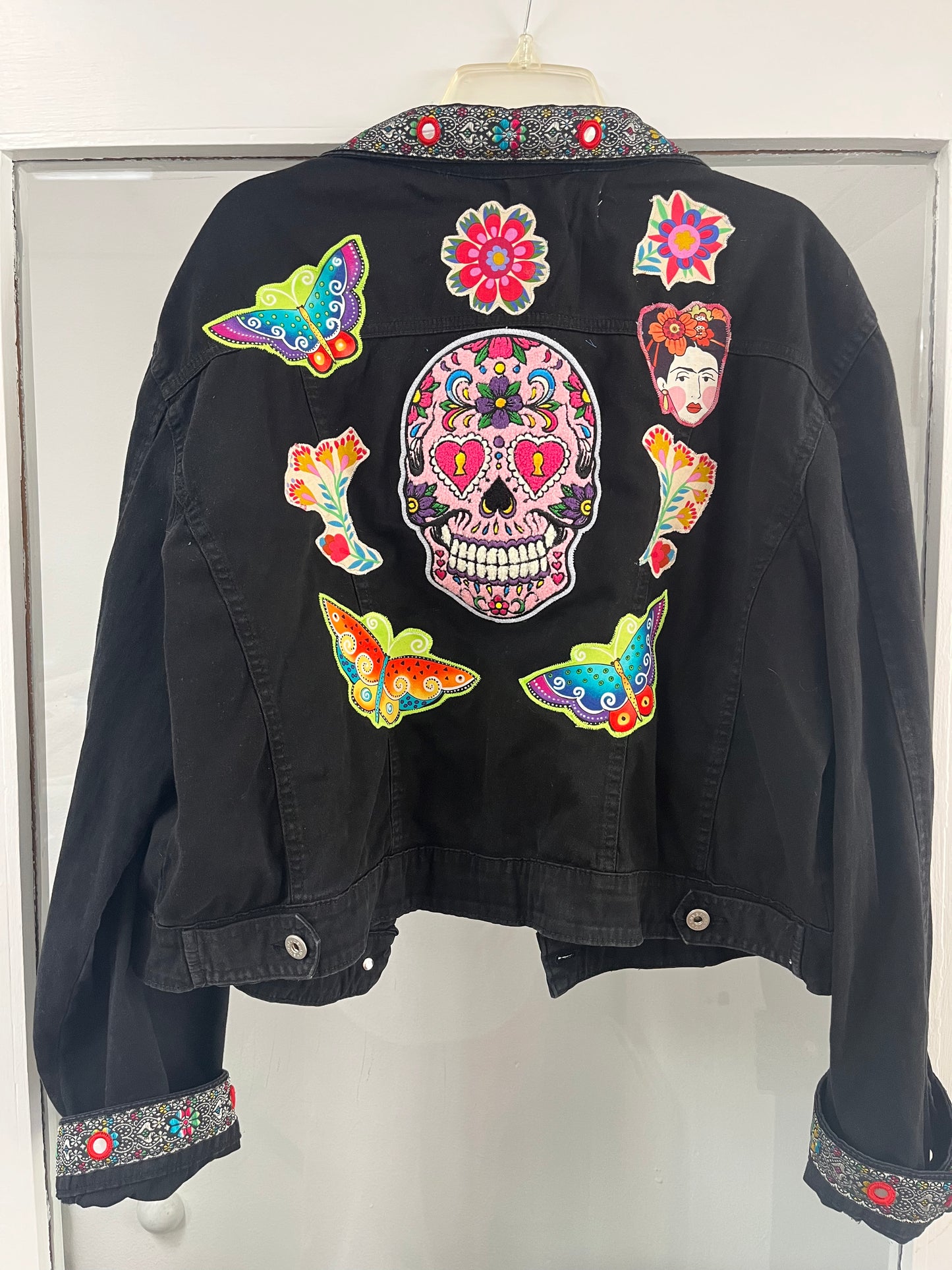 Black jacket with colorful patches including a skull design on a white background