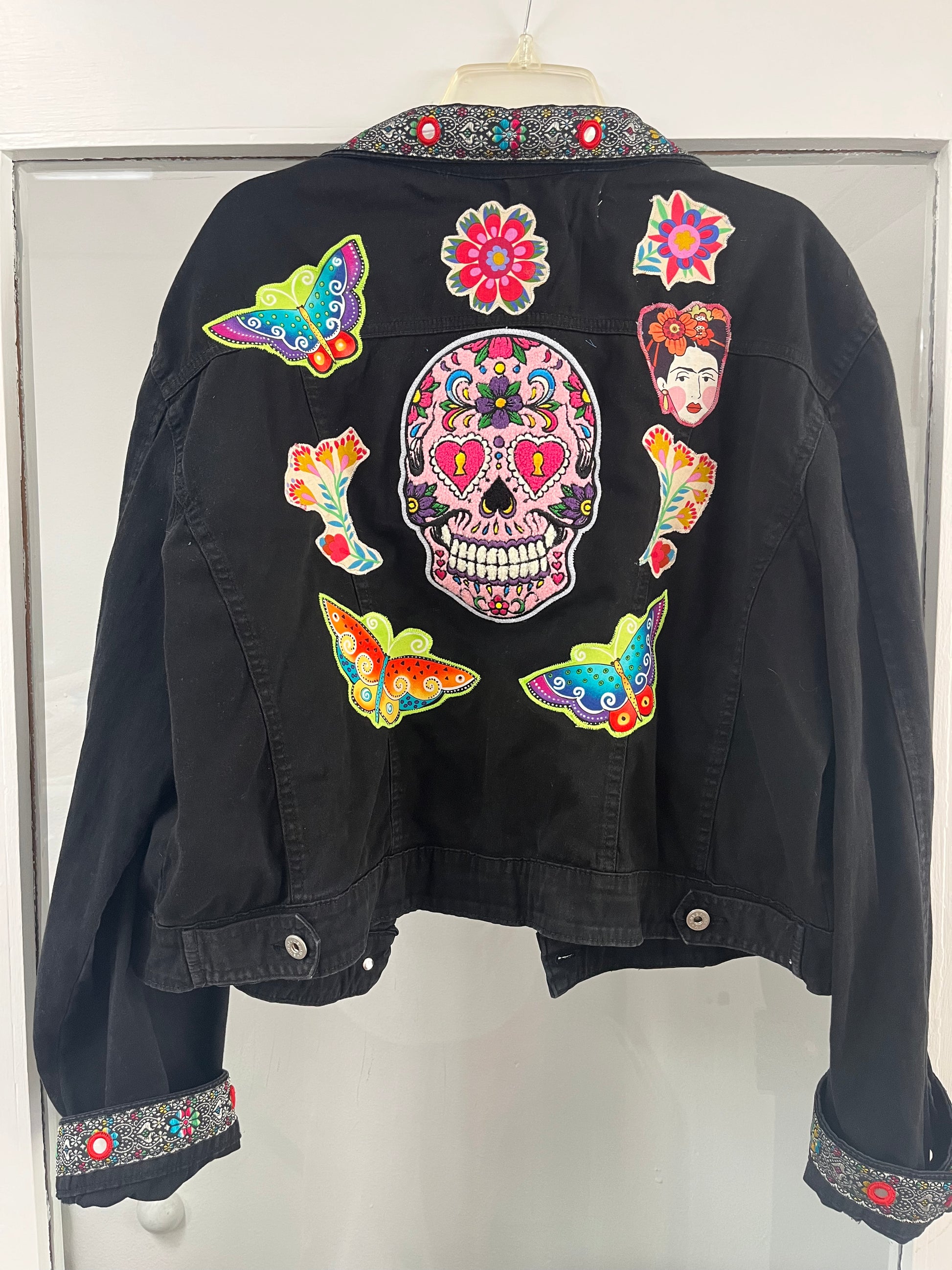 Black jacket with colorful patches including a skull design on a white background