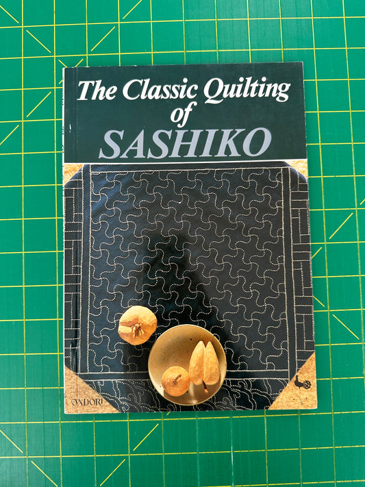 Book titled 'The Classic Quilting of Sashiko' on a green grid background