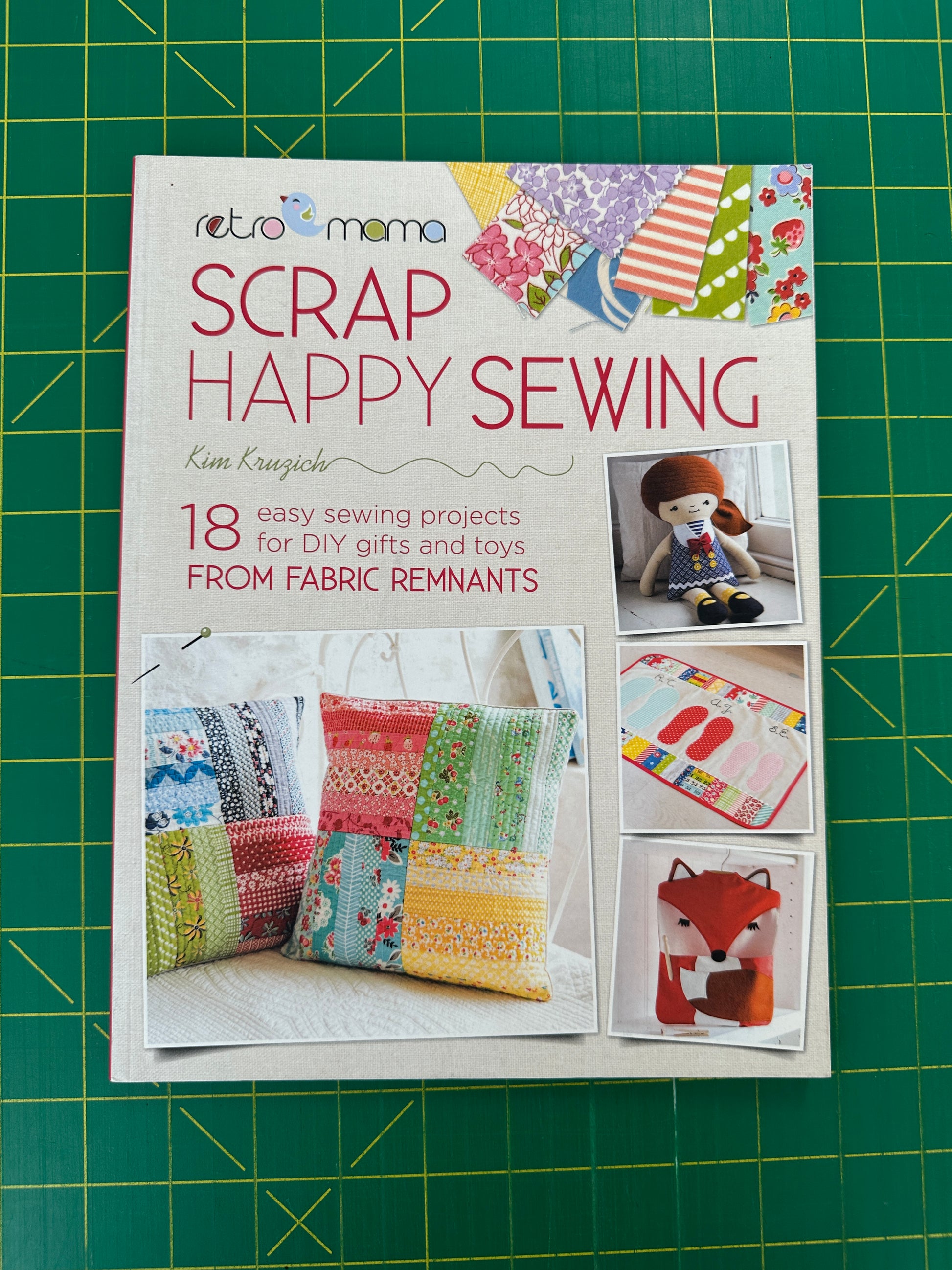 A book titled "Scrap Happy Sewing" on a green cutting mat 
