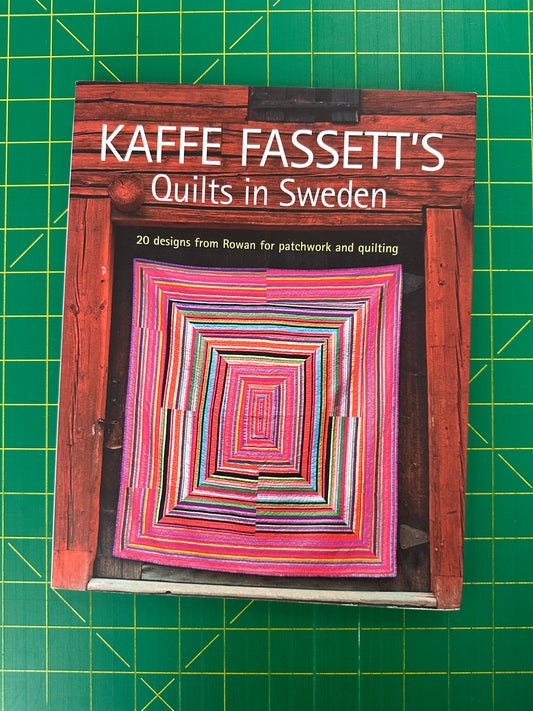Book titled 'Kaffe Fassett's Quilts in Sweden' on a green cutting mat
