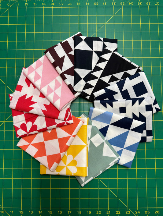 Collection of geometric patterned fabric squares on a green cutting mat.