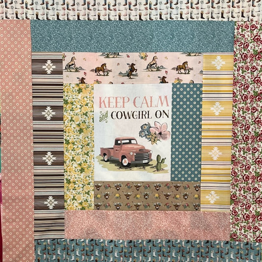 A square quilted fabric panel featuring a central printed patch with the words 'KEEP CALM and COWGIRL ON' above a pink vintage pickup truck, surrounded by multiple western-themed patterned fabric borders including stripes, florals, and cowgirl motifs.
