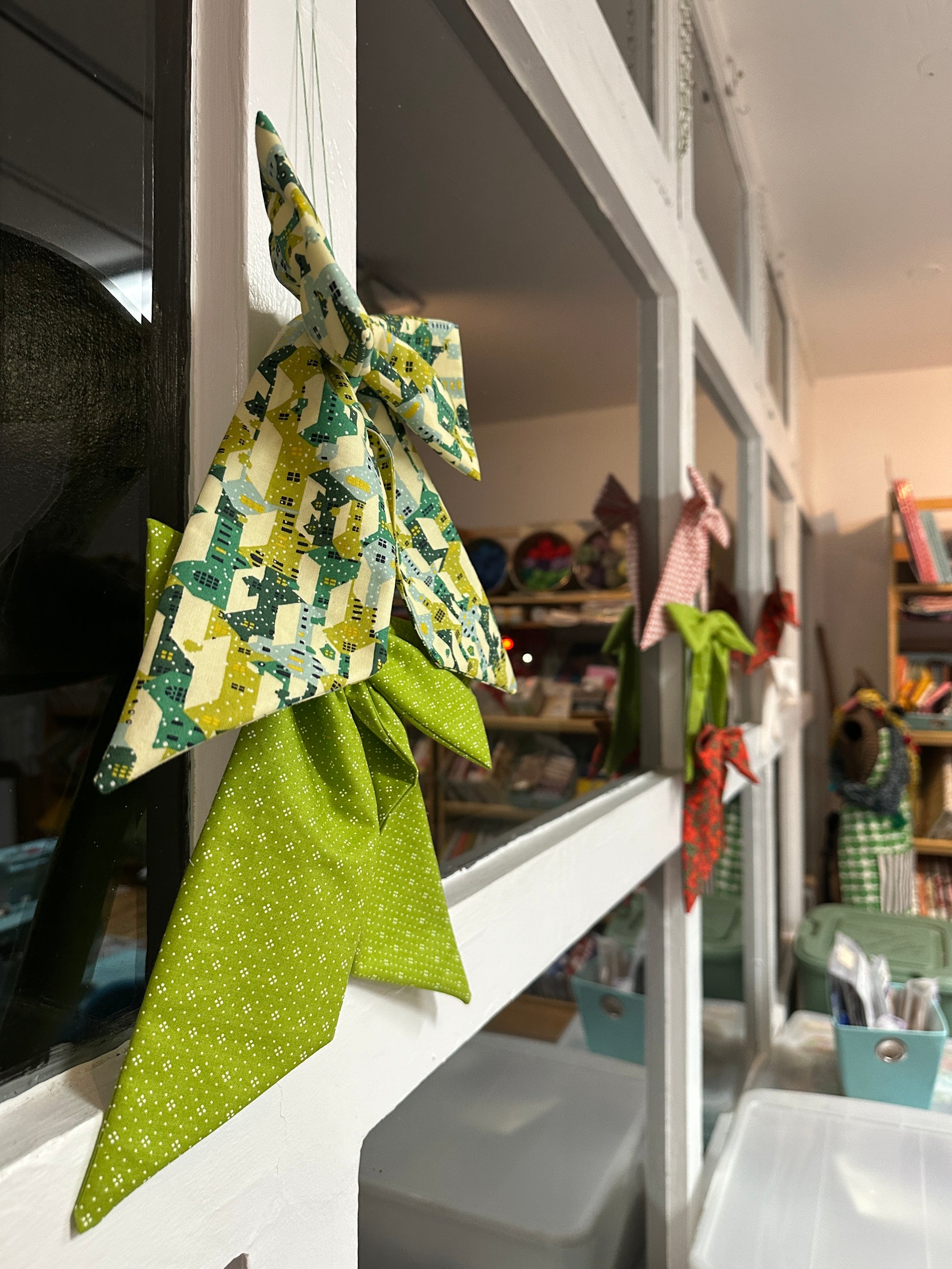 Bows made from green and patterned fabric on windows in a fabric shop at night