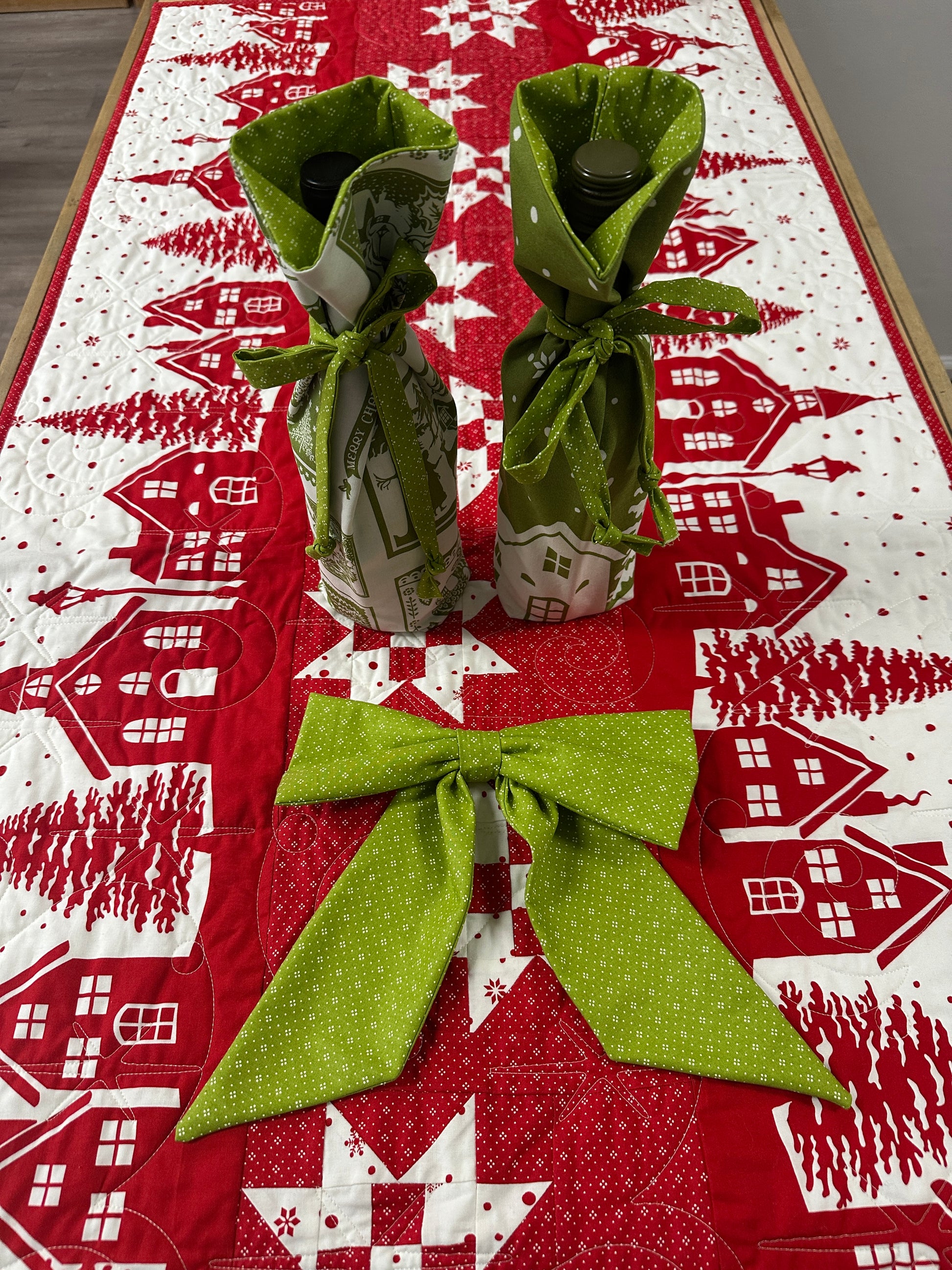 Green fabric windmill on a red and white patterned background with houses and trees.