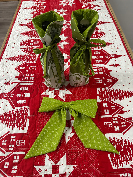 Green fabric windmill on a red and white patterned background with houses and trees.
