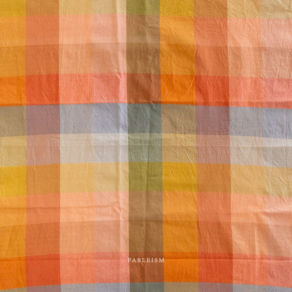 Checkered fabric with autumnal colors and 'Fableism' branding.