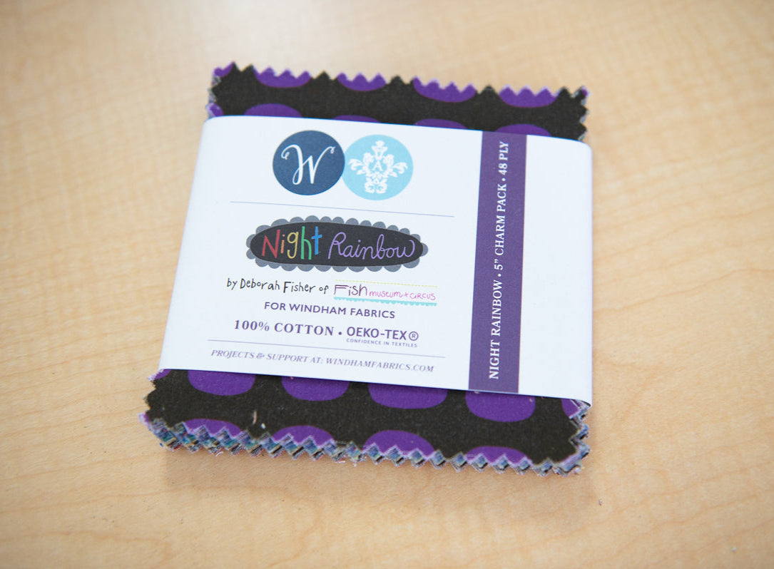 Pack of fabric squares with a Night Rainbow label on a beige background