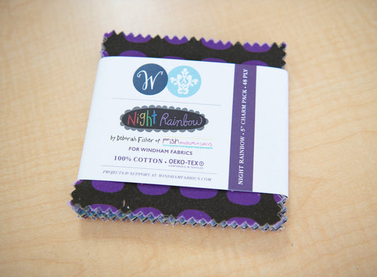 Pack of fabric squares with a Night Rainbow label on a beige background