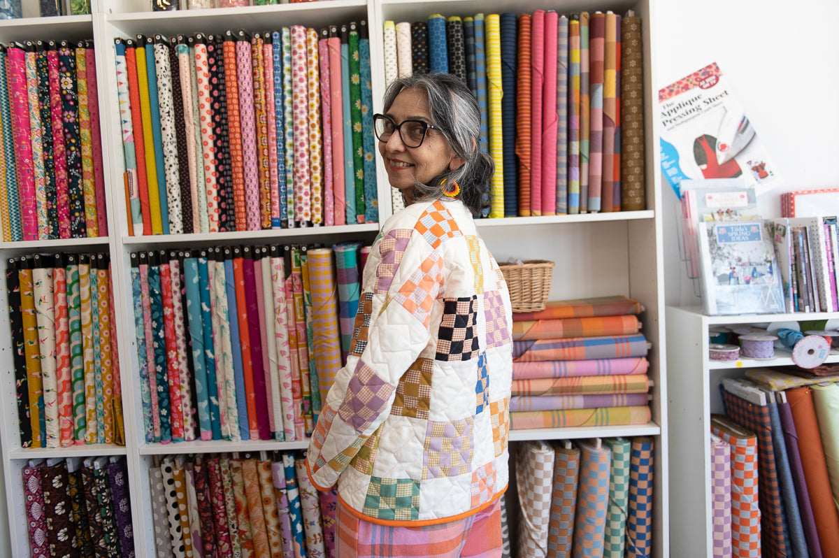 Woman standing in front of a colorful bookshelf filled with books.