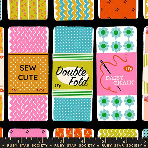 Patterned fabric with various designs and text on a black background, featuring brands like Ruby Star Society.