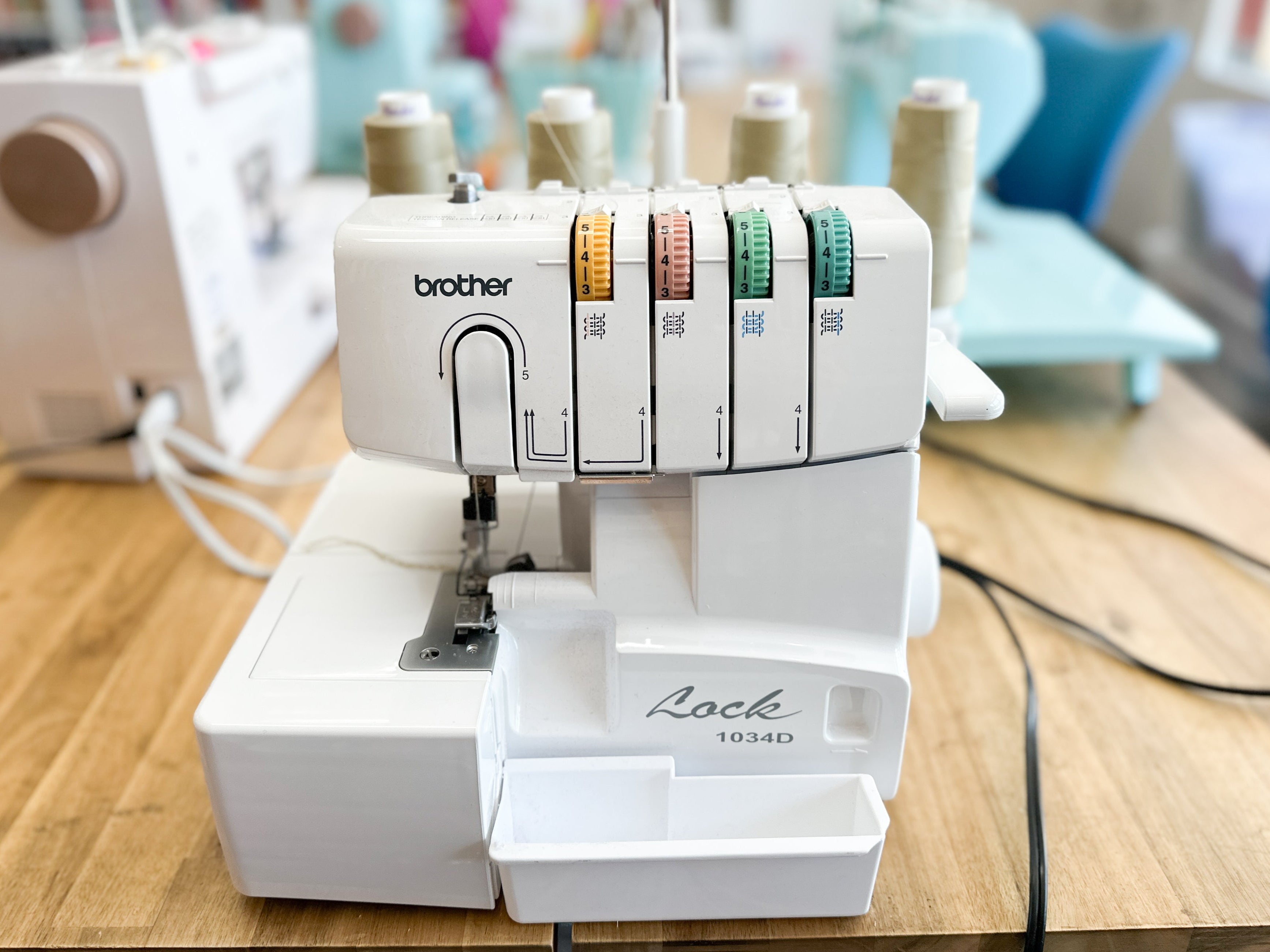 Brother serger machine on a wooden table with spools of thread in the background.