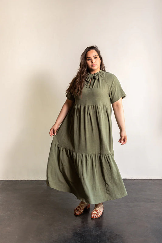 Woman wearing a green dress standing against a plain background