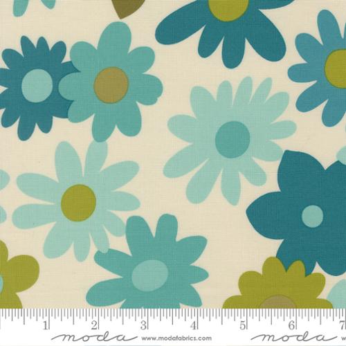 Blue flowers with green or blue centers on a cream background with a moda ruler at the bottom