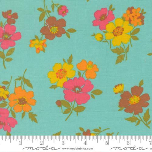Pink, yellow, orange, and brown flowers with green stems on a blue colored background with Moda ruler at the bottom