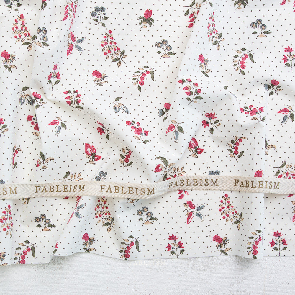 Floral fabric with a ribbon displaying 'Fableism' on a textured surface