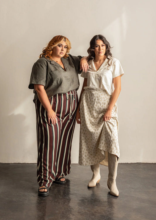 Two women standing together wearing Donnie blouses against a plain background