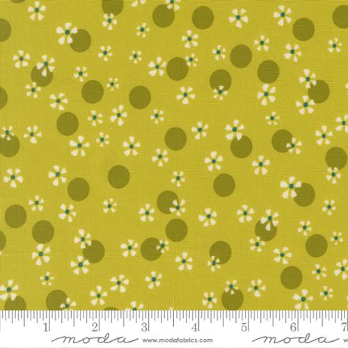White flowers and green dots on a green background with the Moda ruler below