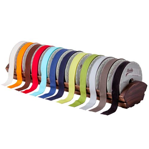 Set of ribbon spools in various colors on a wooden stand against a white background