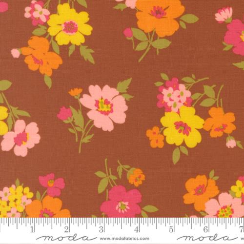 Pink, yellow, and orange flowers with green stems on a brown background with Moda ruler at the bottom