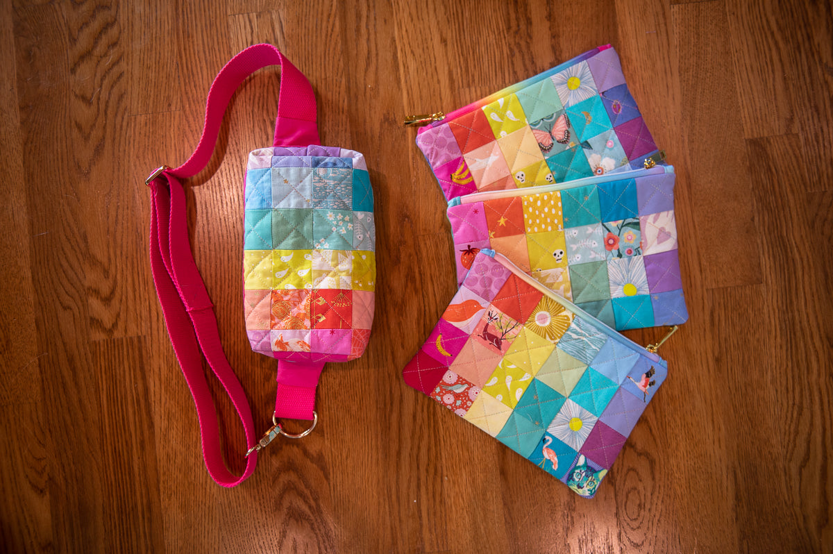 Colorful quilted pouches with a pink strap on a wooden surface