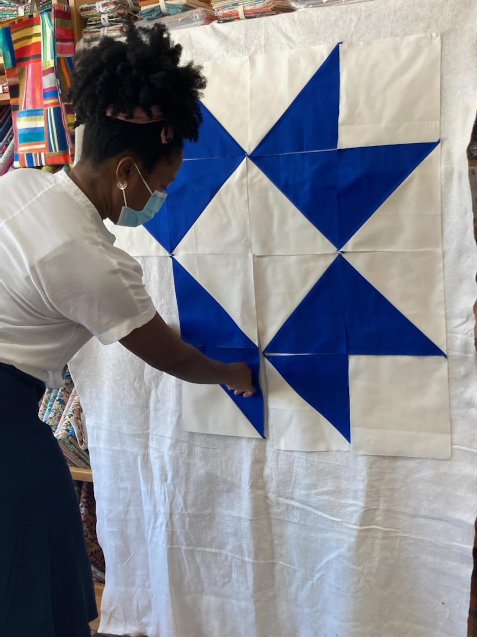 a brown skinned girl lining up blue and white quilt blocks